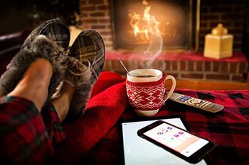 Persona descansando junto a la chimenea con la app de la casa en una tablet
